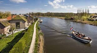 Sloep vaart door Nederlandse rivier