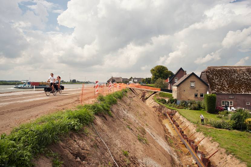 Dijkverhoging in aanbouw, rivier, fietsers