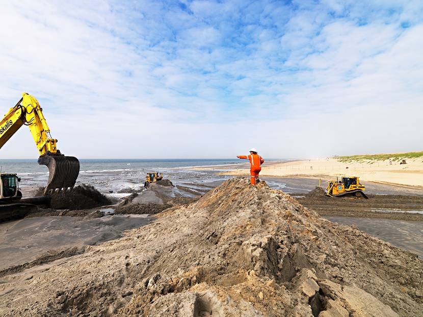 Graafmachine aan het werk op het strand