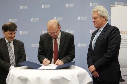 Staatssecretaris Atsma (IenM) (midden) ondertekent de Deltawet in het bijzijn van de deltacommissaris (rechts) en de algemene rijksarchivaris, Martin Berendse (links)