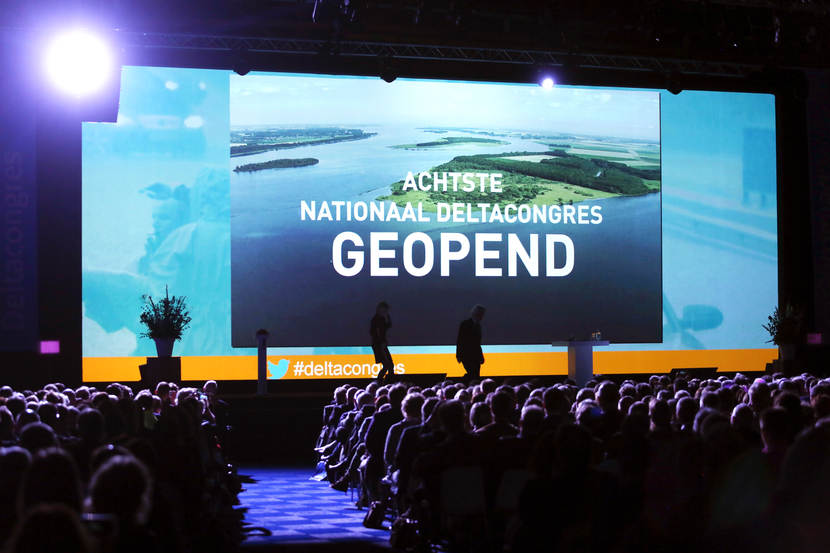 Dia van de opening van het congres, terwijl publiek toekijkt