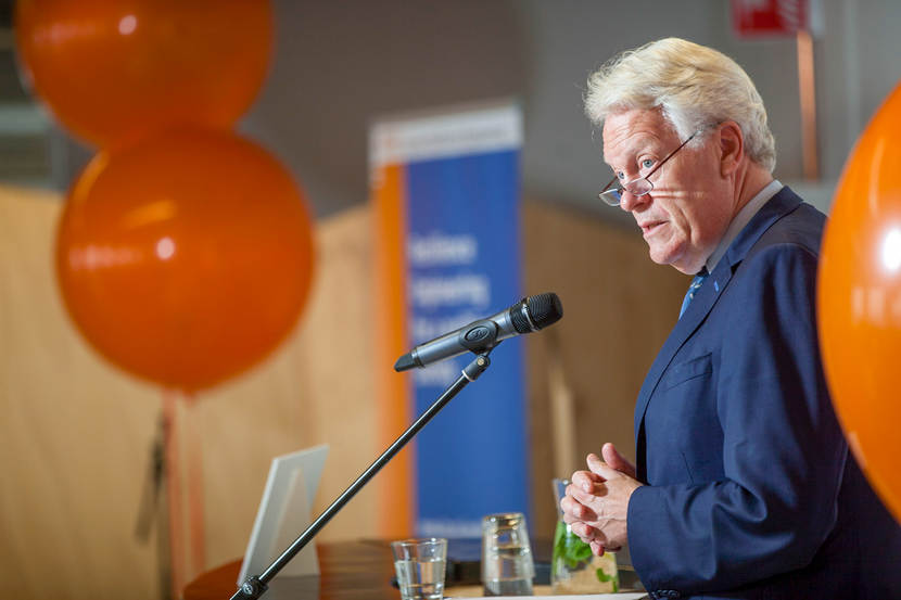 Wim Kuijken spreekt een groep toe naast oranje ballonnen