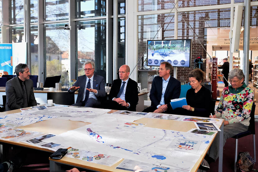 Werk Bespreking rond een tafel met tekeningen op tafel