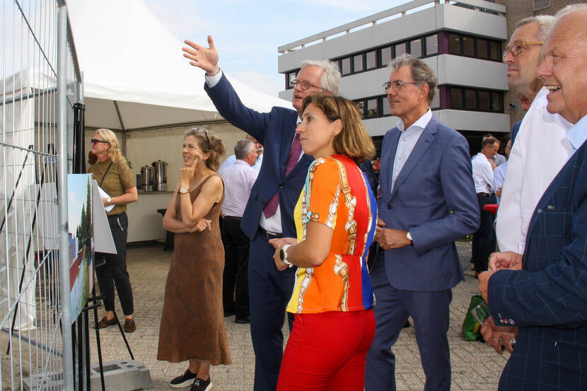 Deltacommissaris Peter Glas wijst naar een hek tijdens het werkbezoek bij Twents waternet